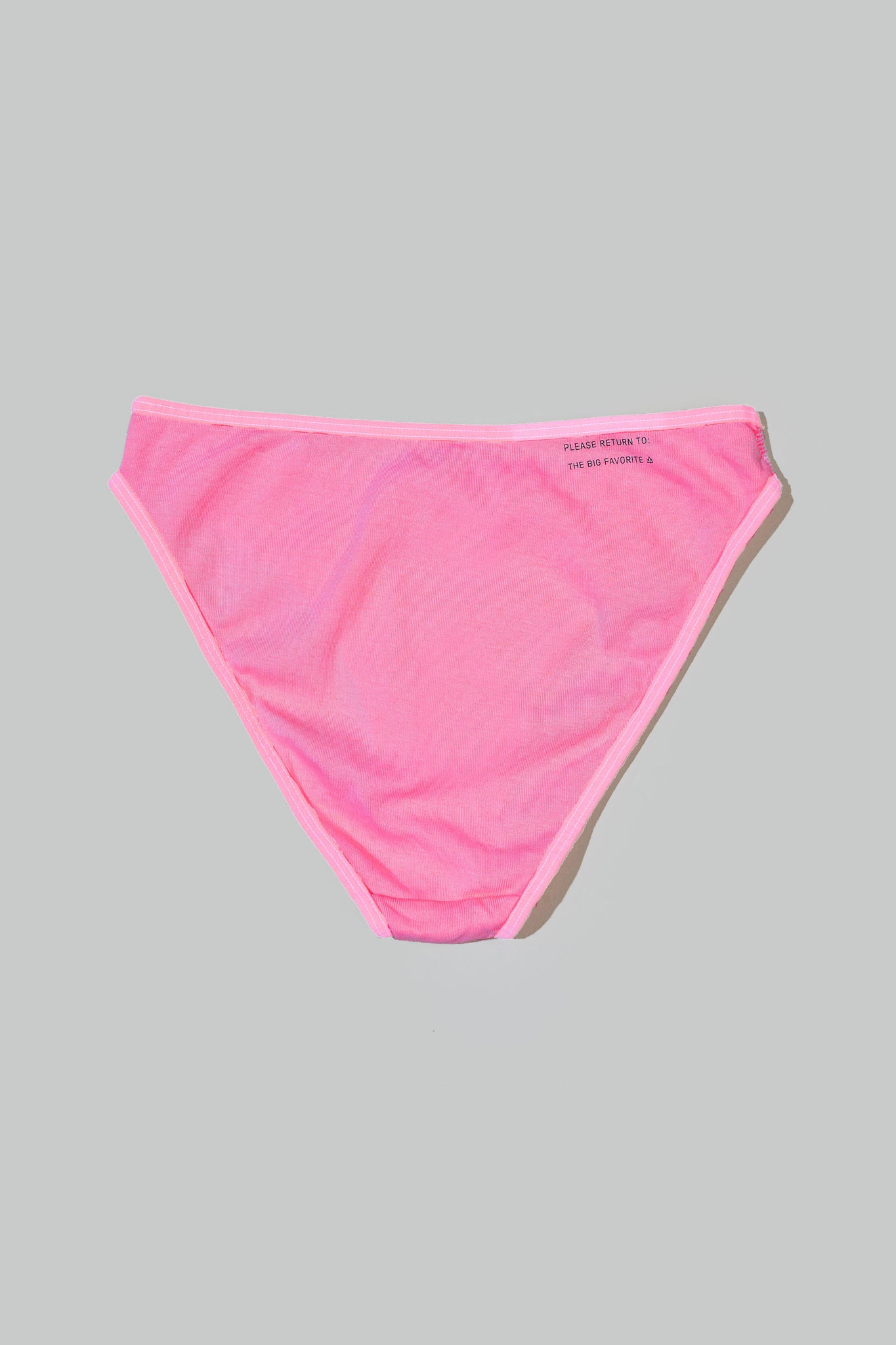 a bikini brief in hot pink laid on the floor