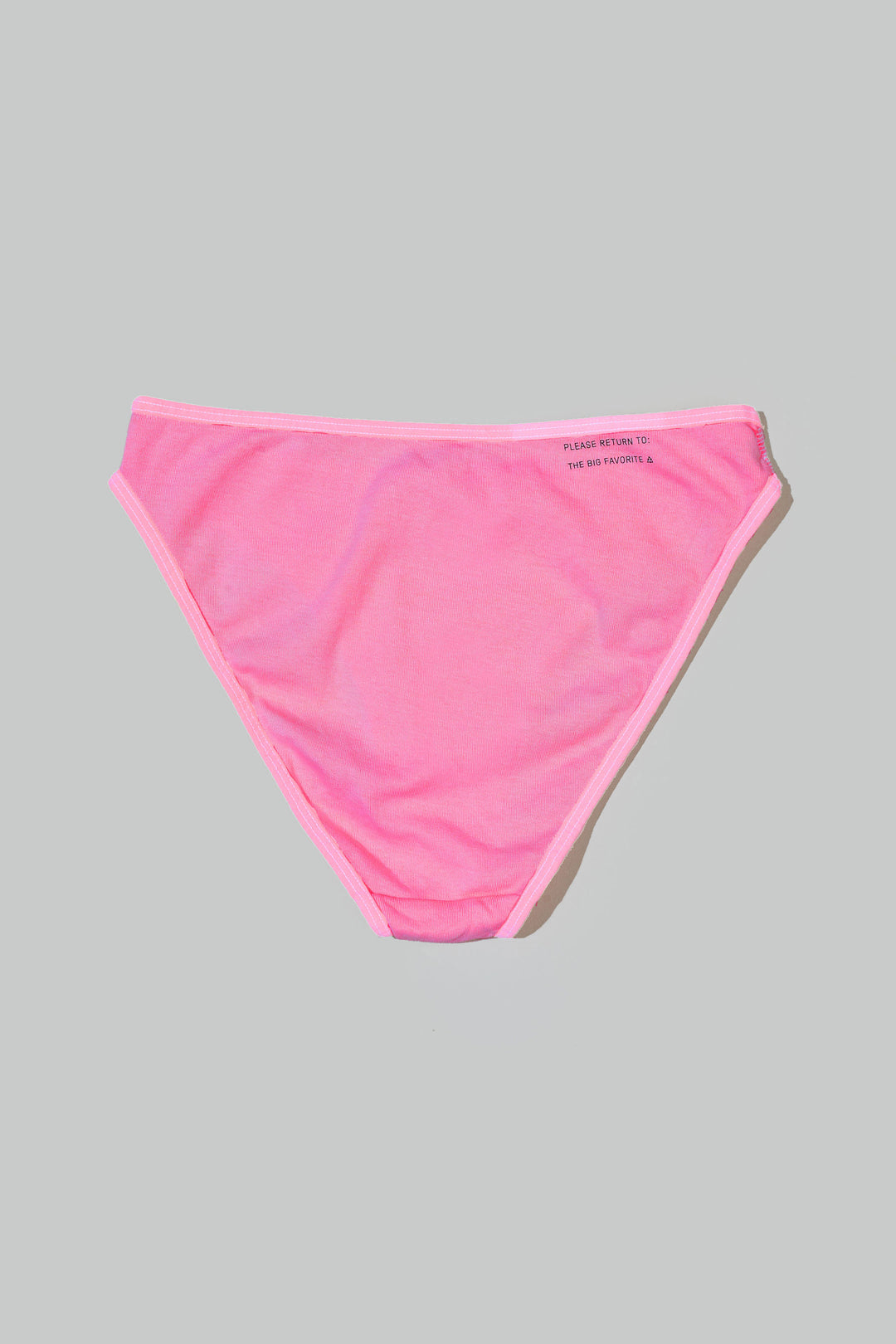 a bikini brief in hot pink laid on the floor