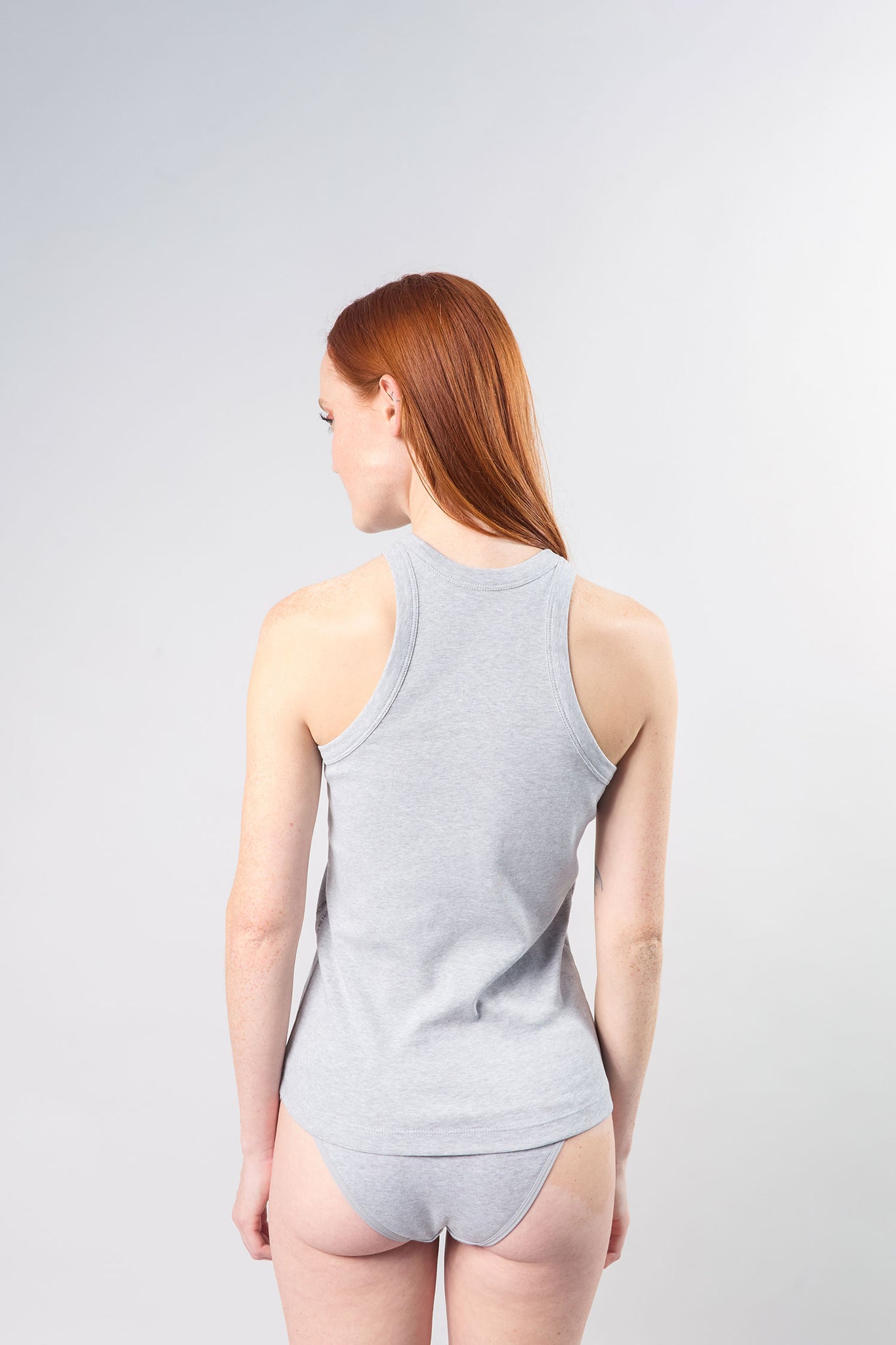 woman wearing 90s tank facing back and showing the cutout shape on the back armhole