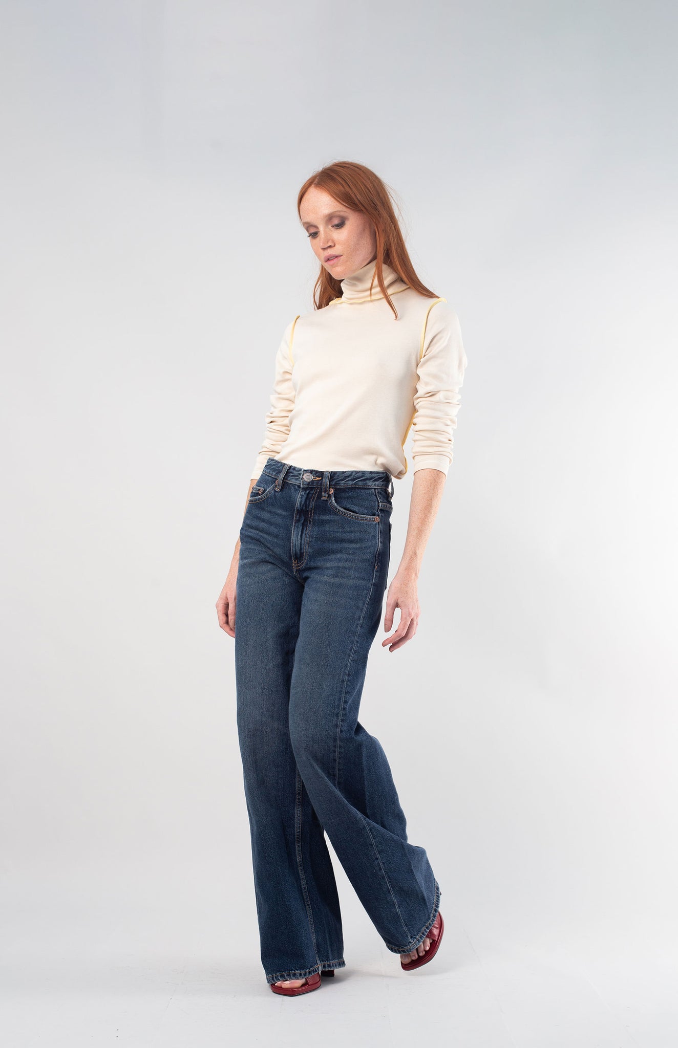 woman with red hair wearing the undyed turtleneck with wide leg jeans and red shoes