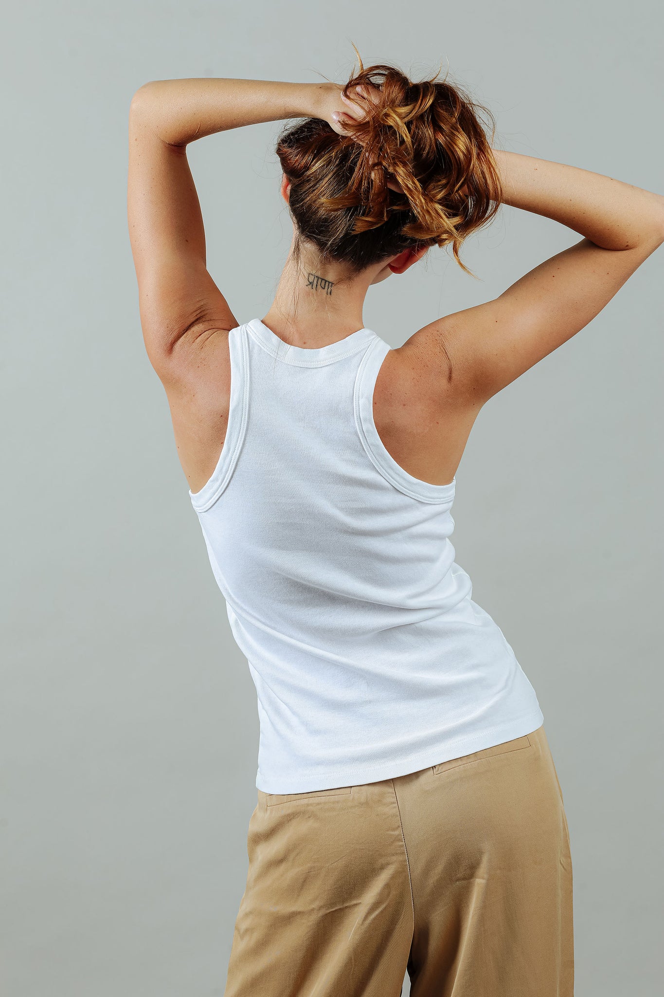 woman wearing the 90s tank in white from the back with tattoo on her neck